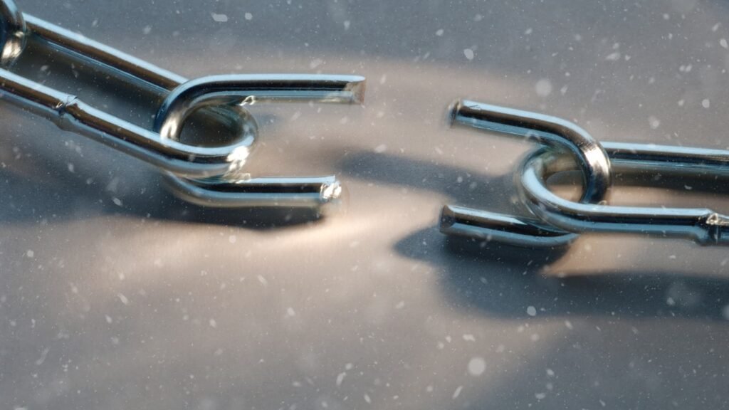 תקריב של חוליה בשרשרת מתכת נשברת, כשמתוכה מתפרצים רסיסי זהב ואור. דימוי ויזואלי לשחרור חסמים וצמיחה עסקית.